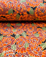 Japanese chiyogami paper featuring large red chrysanthemums with green leaves on a black background with metallic gold details.