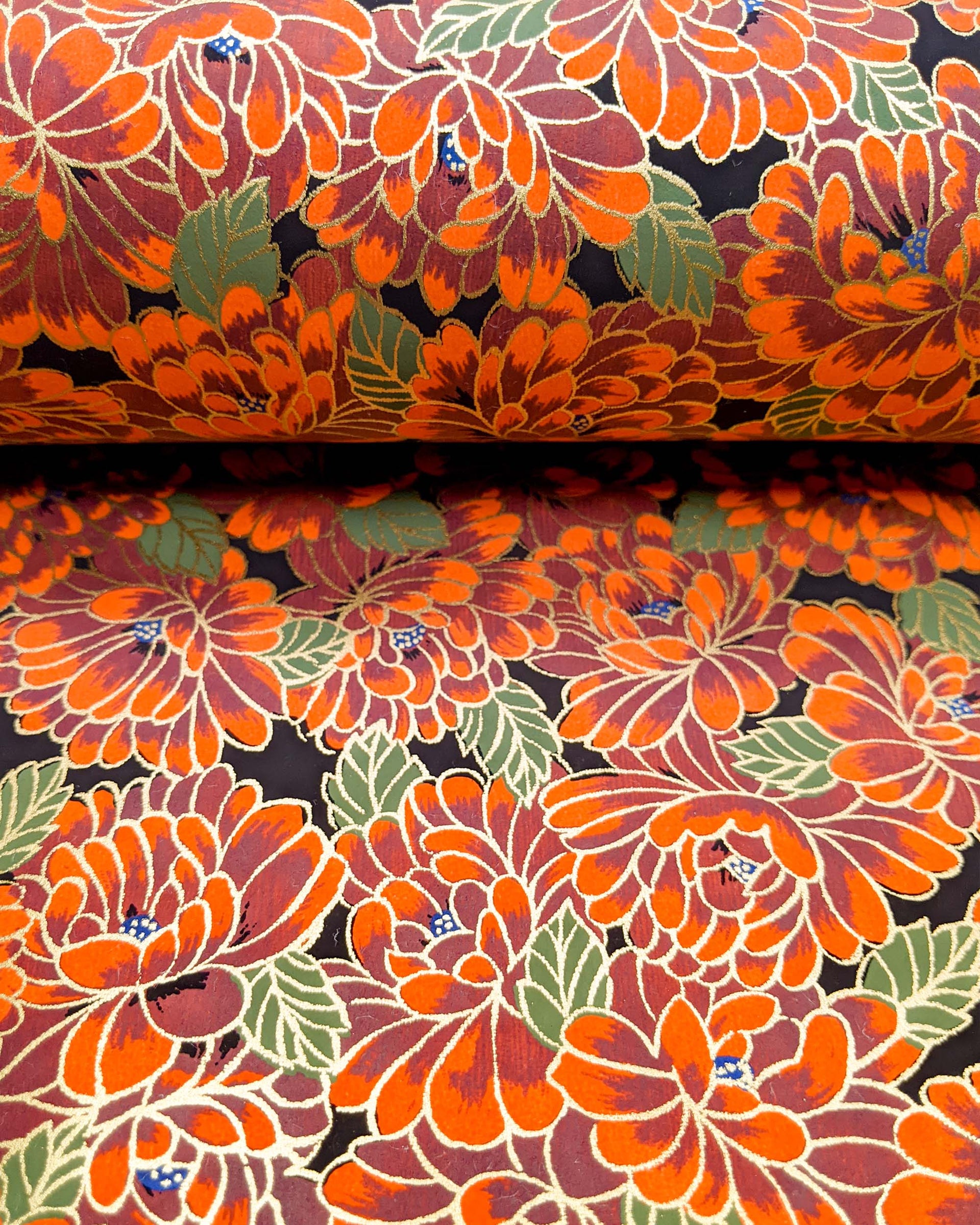 Japanese chiyogami paper featuring large red chrysanthemums with green leaves on a black background with metallic gold details.