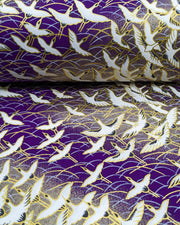 Japanese chiyogami paper featuring white flying cranes in a zigzag formation on a dark purple background with metallic gold details.