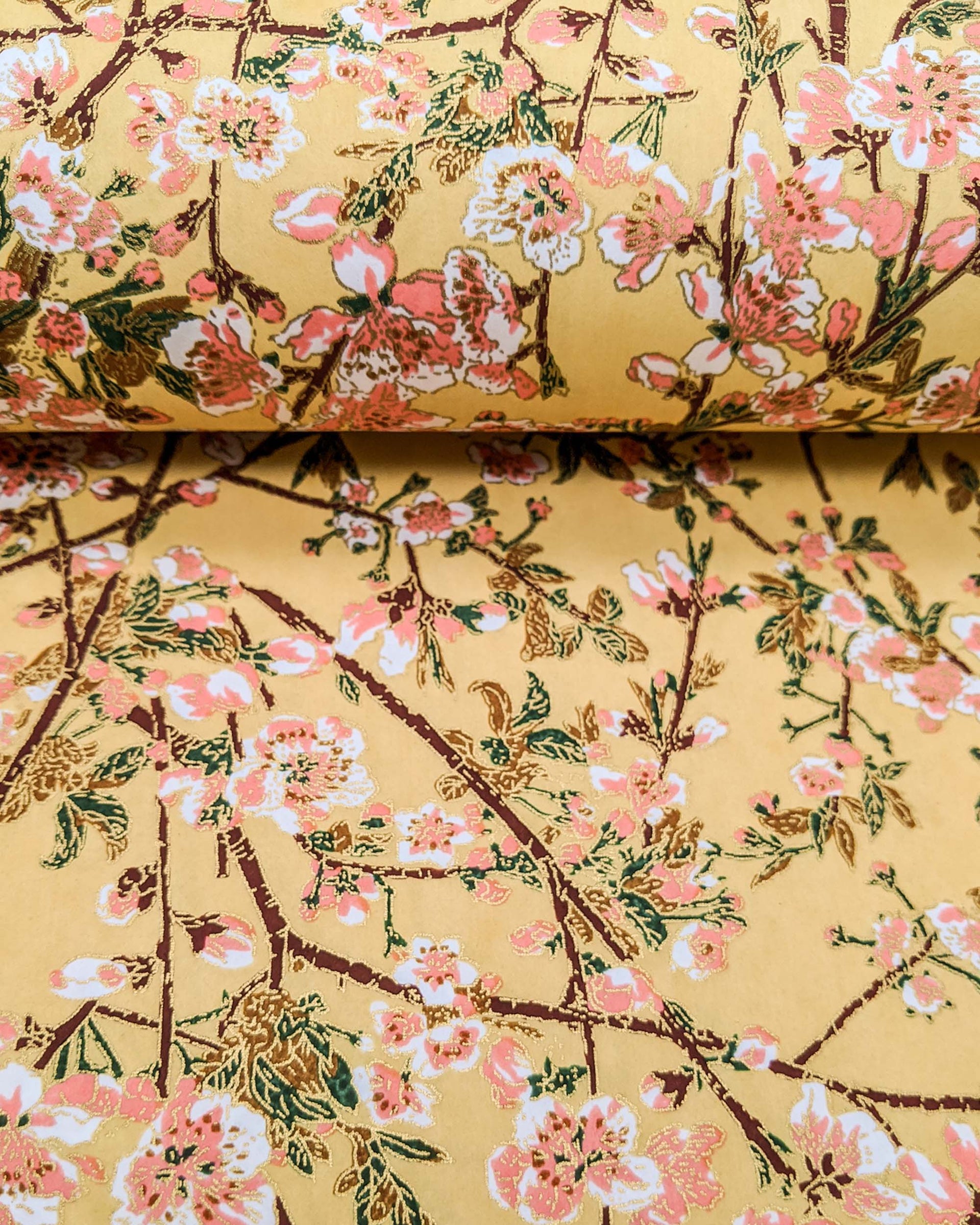 Japanese chiyogami paper featuring pink and white plum blossoms with dark brown branches and green leaves on a beige background with metallic gold details.