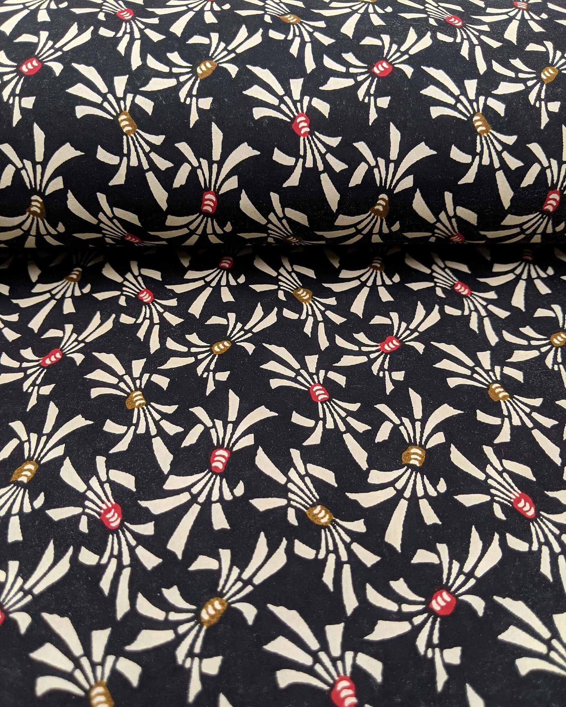 Japanese chiyogami paper featuring cream colored Japanese noshi ribbons with red and brown centers on a black background.