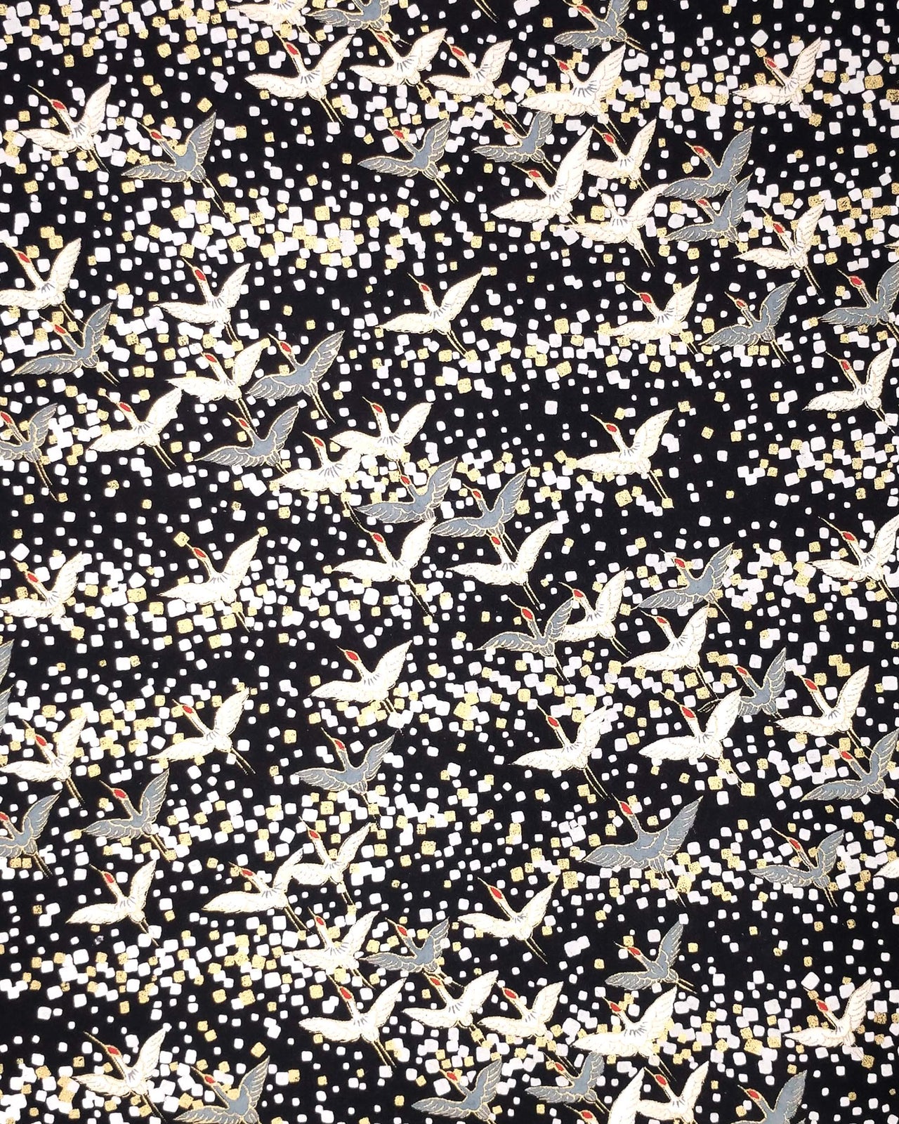 Japanese chiyogami paper featuring flying white and gray cranes with red heads on a black background with metallic gold and silver details.