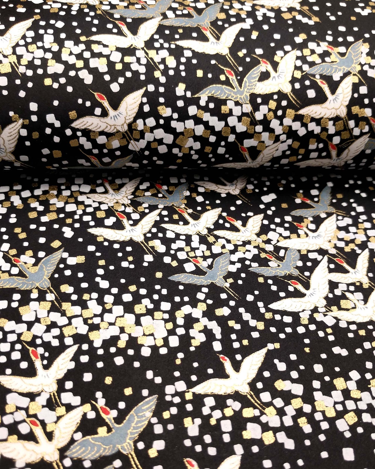 Japanese chiyogami paper featuring flying white and gray cranes with red heads on a black background with metallic gold and silver details.