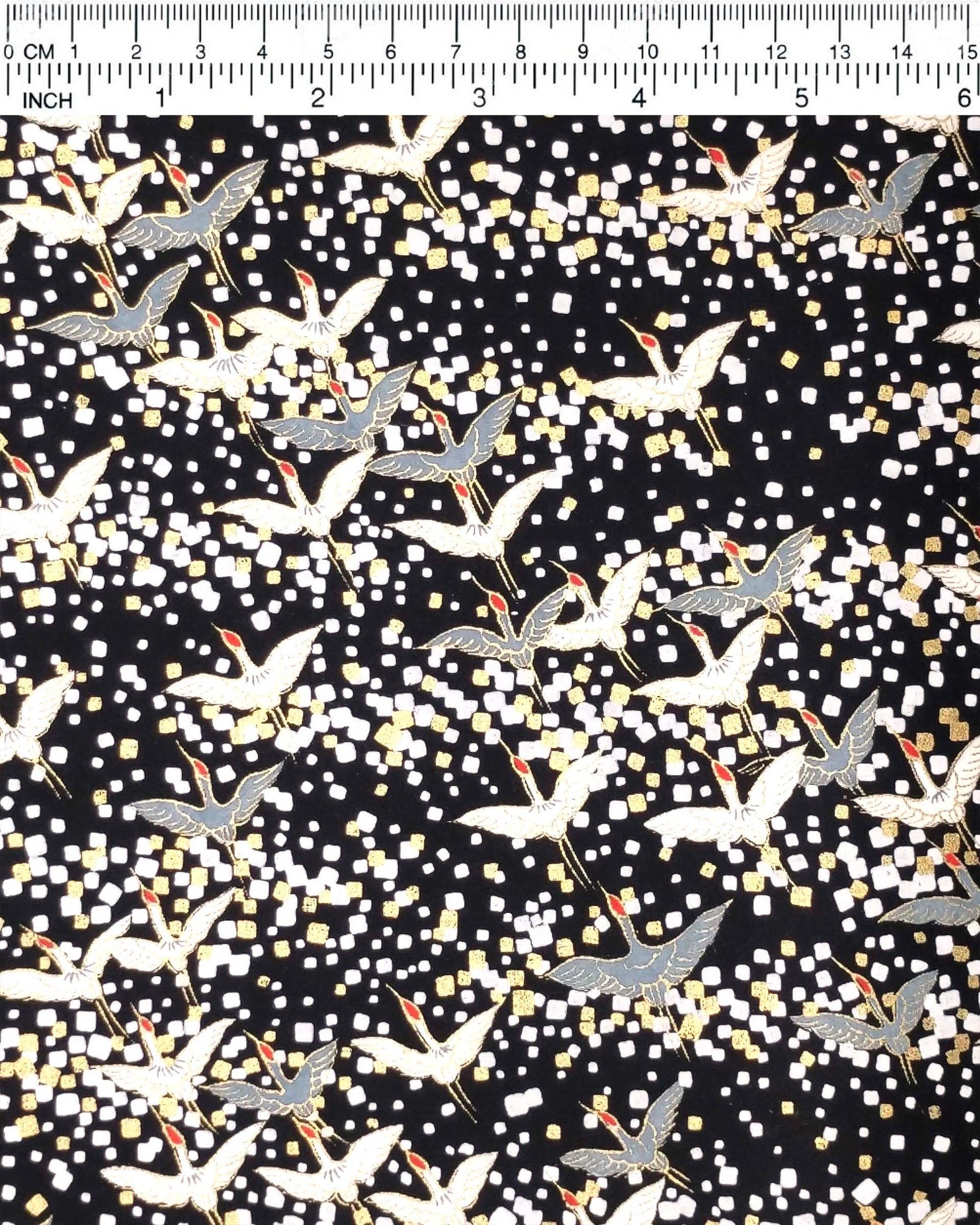 Japanese chiyogami paper featuring flying white and gray cranes with red heads on a black background with metallic gold and silver details.