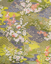 Japanese chiyogami paper featuring small white, green, and orange flowers on a gray and green background embedded with various traditional Japanese motifs with metallic gold details.