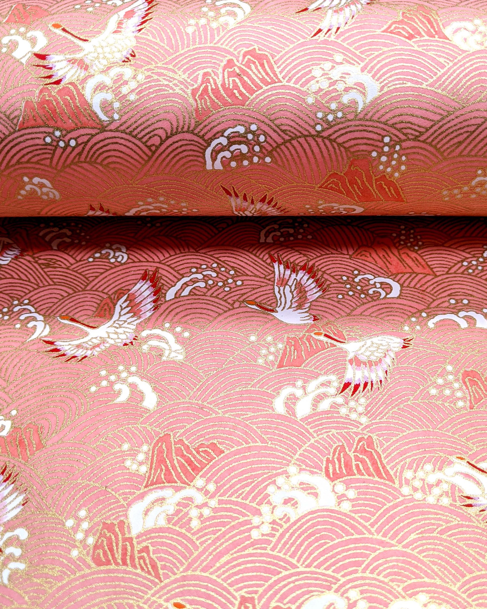 Japanese chiyogami paper featuring white and pink cranes flying over a pink wave background with metallic gold details.