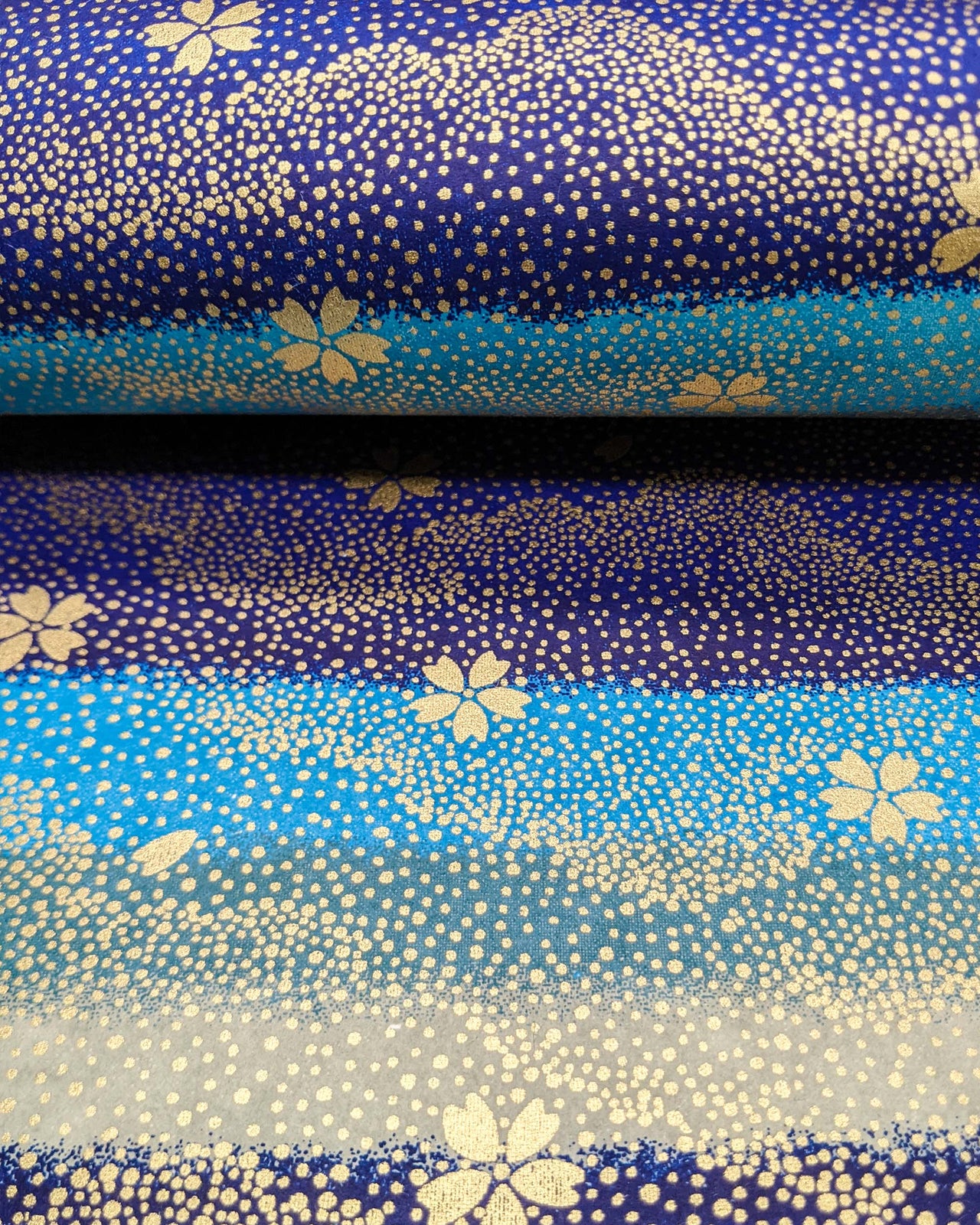 Japanese chiyogami paper featuring gold cherry blossoms on a blue and gray striped background with metallic gold details.