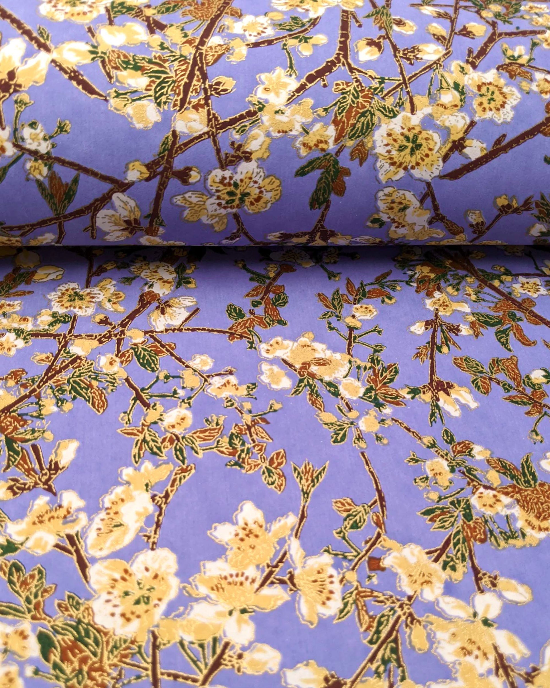 Japanese chiyogami paper featuring beige and white plum blossoms with dark brown branches and green leaves on a purple background with metallic gold details.