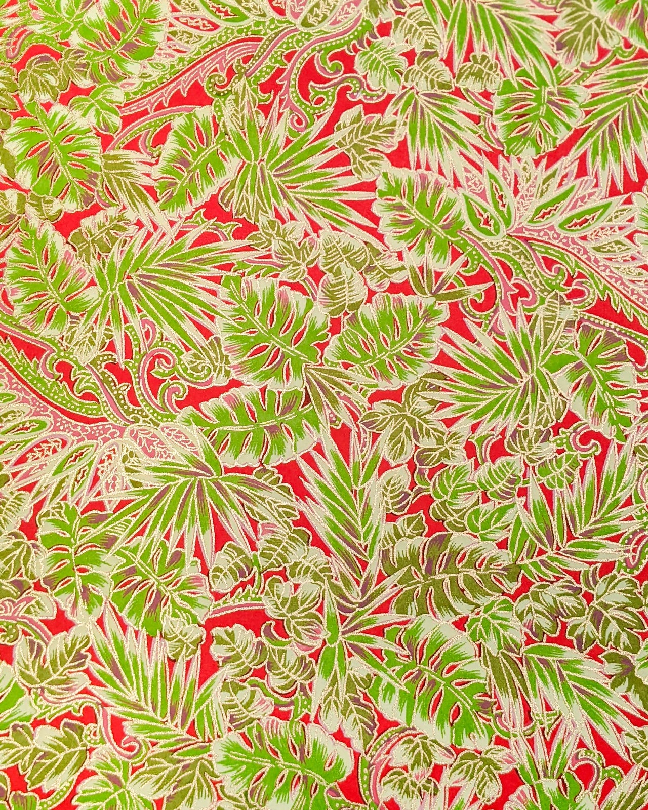 Japanese chiyogami paper featuring green and pink frond leaves on a red background with metallic gold details.