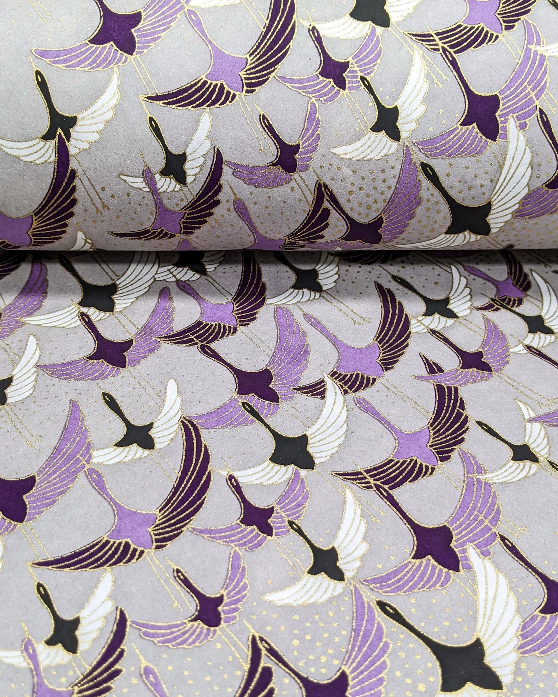 Japanese chiyogami paper featuring purple, black, and white flying cranes on a gray background with metallic gold details.