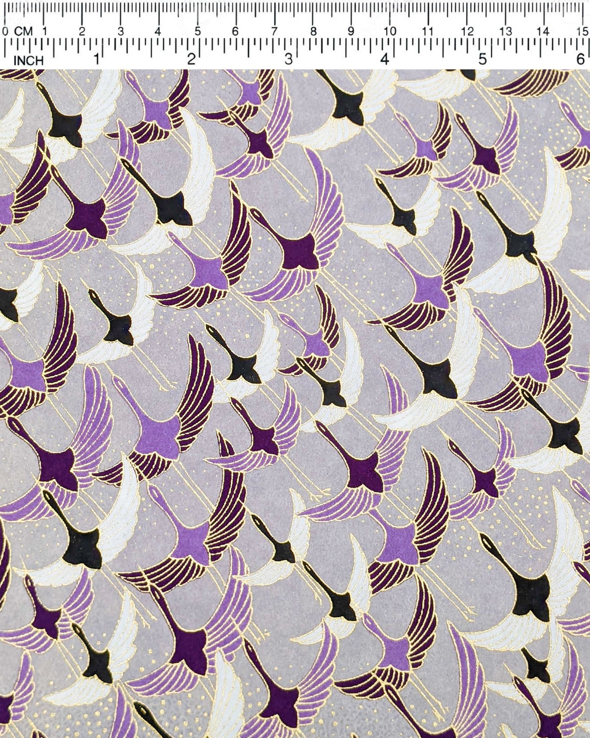 Japanese chiyogami paper featuring purple, black, and white flying cranes on a gray background with metallic gold details.