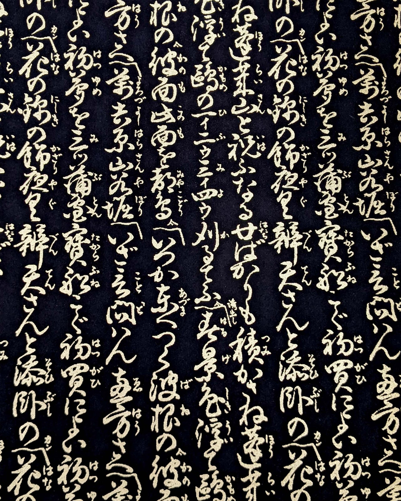 Japanese chiyogami paper featuring vertical metallic gold calligraphy on a black background.