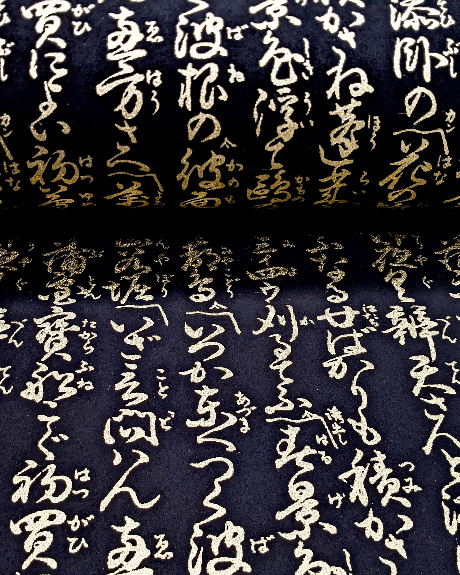 Japanese chiyogami paper featuring vertical metallic gold calligraphy on a black background.