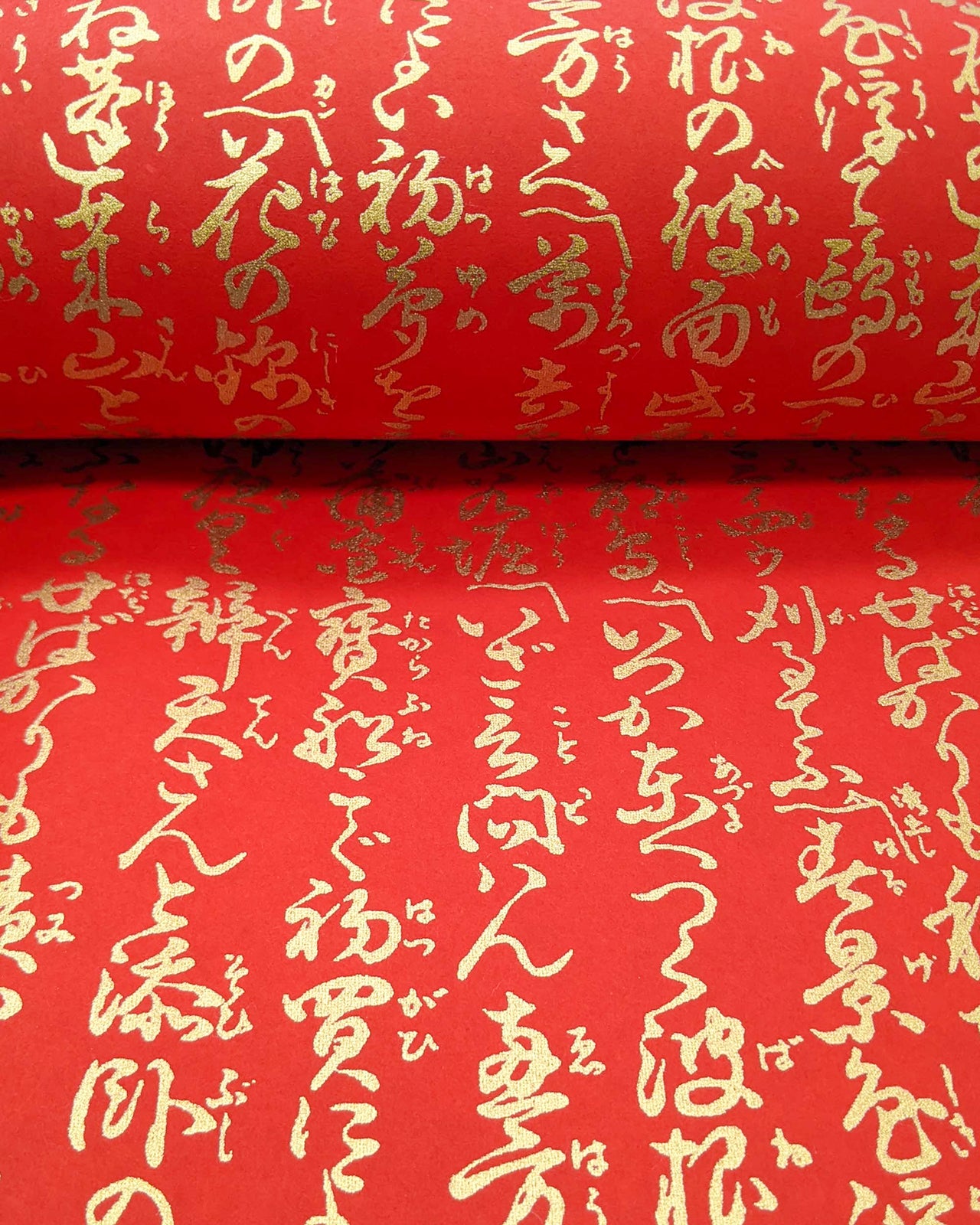 Japanese chiyogami paper featuring vertical metallic gold calligraphy on a red background.