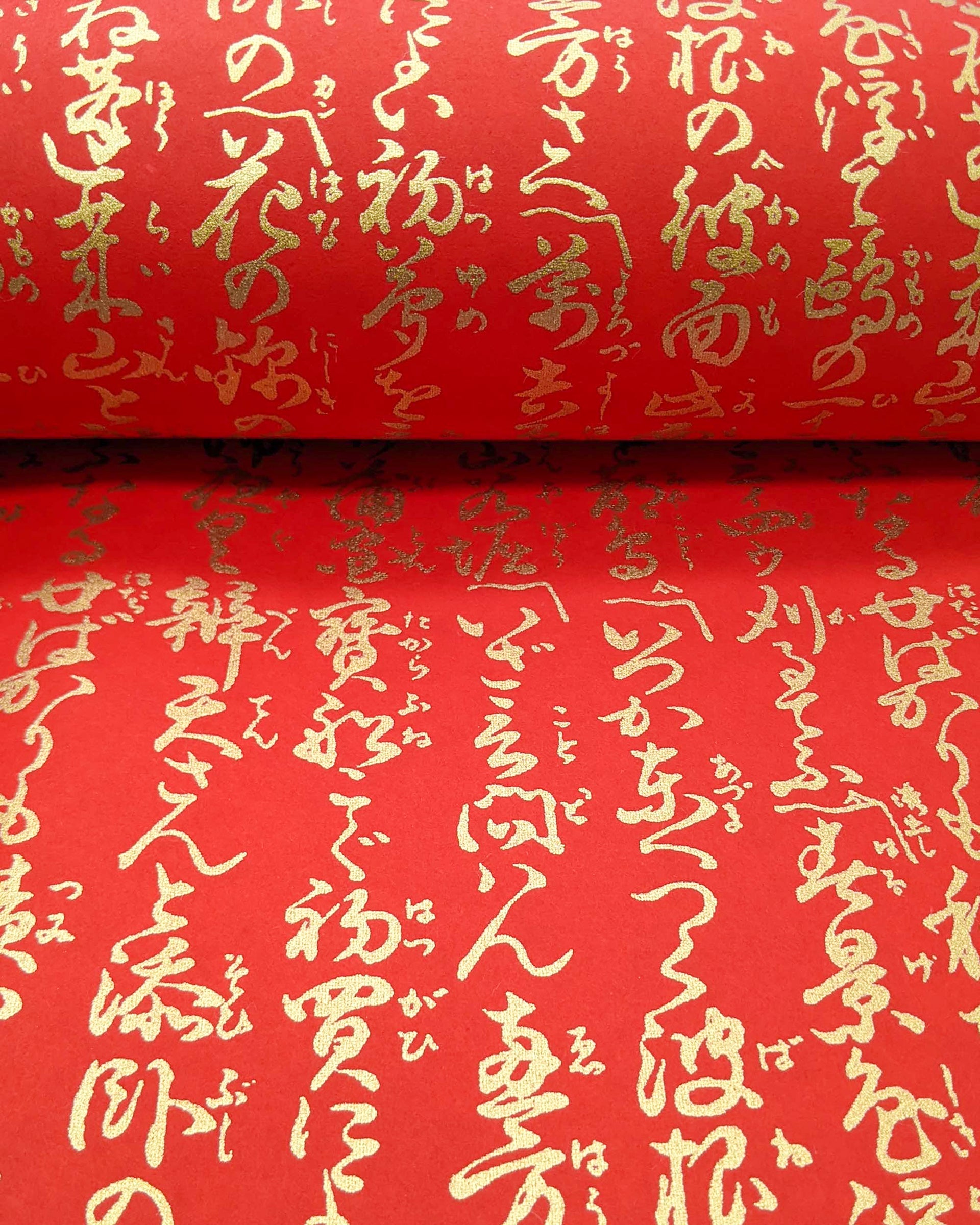 Japanese chiyogami paper featuring vertical metallic gold calligraphy on a red background.