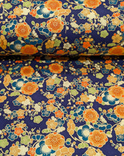 Japanese chiyogami paper featuring orange, blue, green, and cream plum blossoms on a dark blue background with metallic gold details.