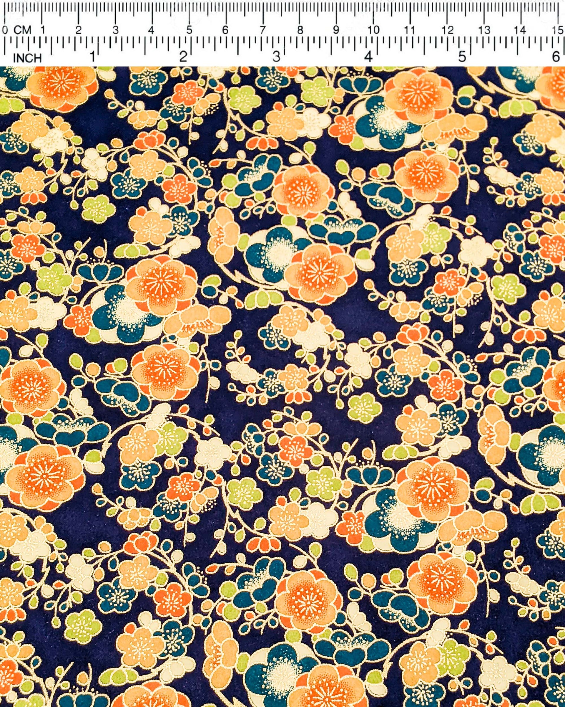 Japanese chiyogami paper featuring orange, blue, green, and cream plum blossoms on a dark blue background with metallic gold details.