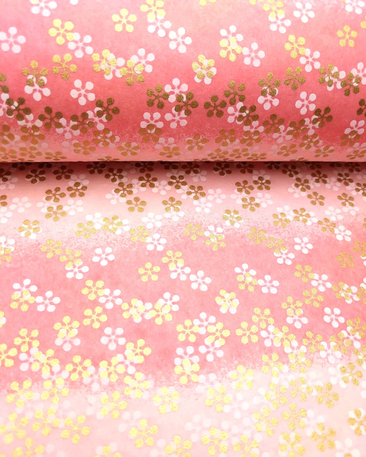 Japanese chiyogami paper featuring metallic gold and white round blossoms on a pink gradient background.