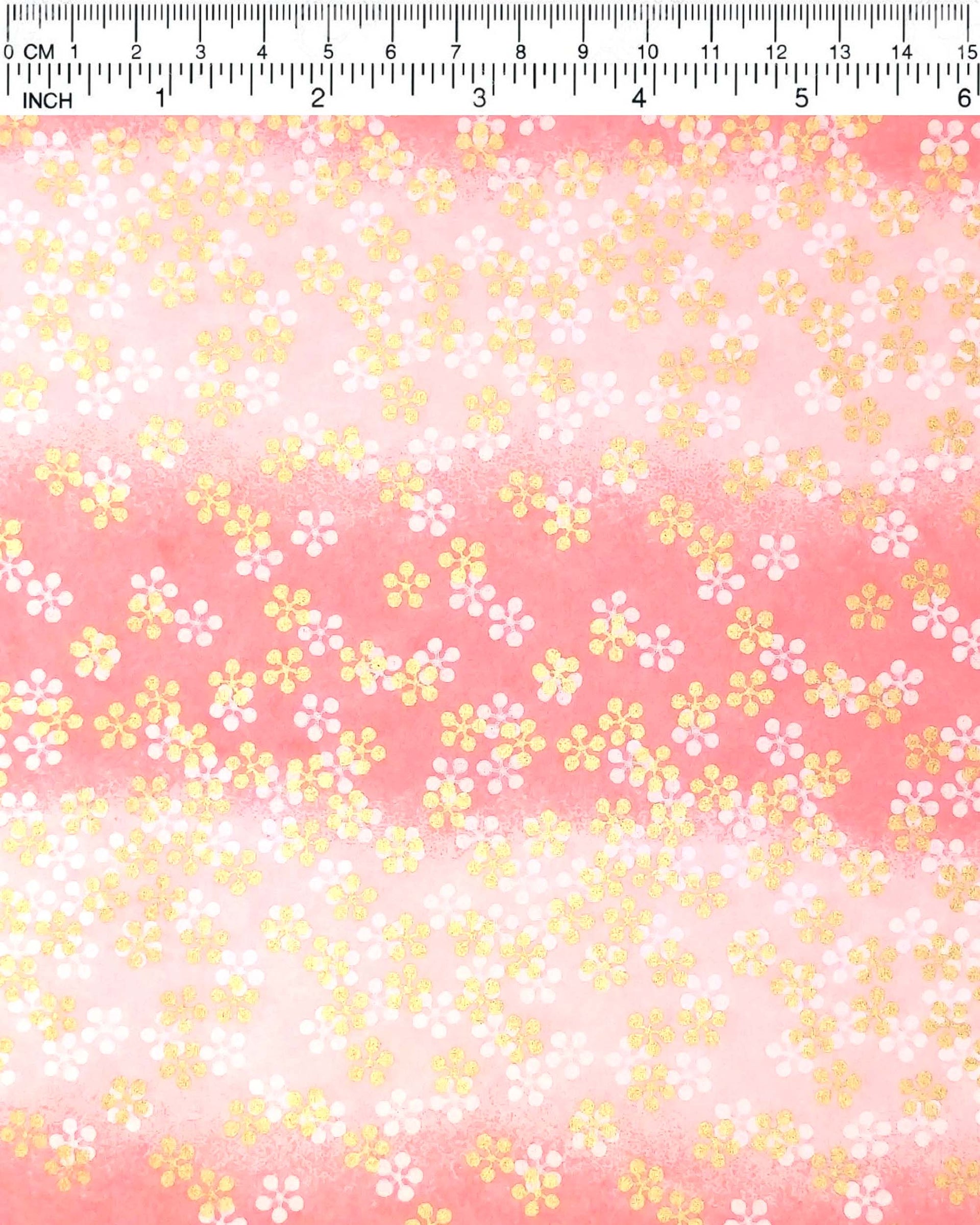 Japanese chiyogami paper featuring metallic gold and white round blossoms on a pink gradient background.