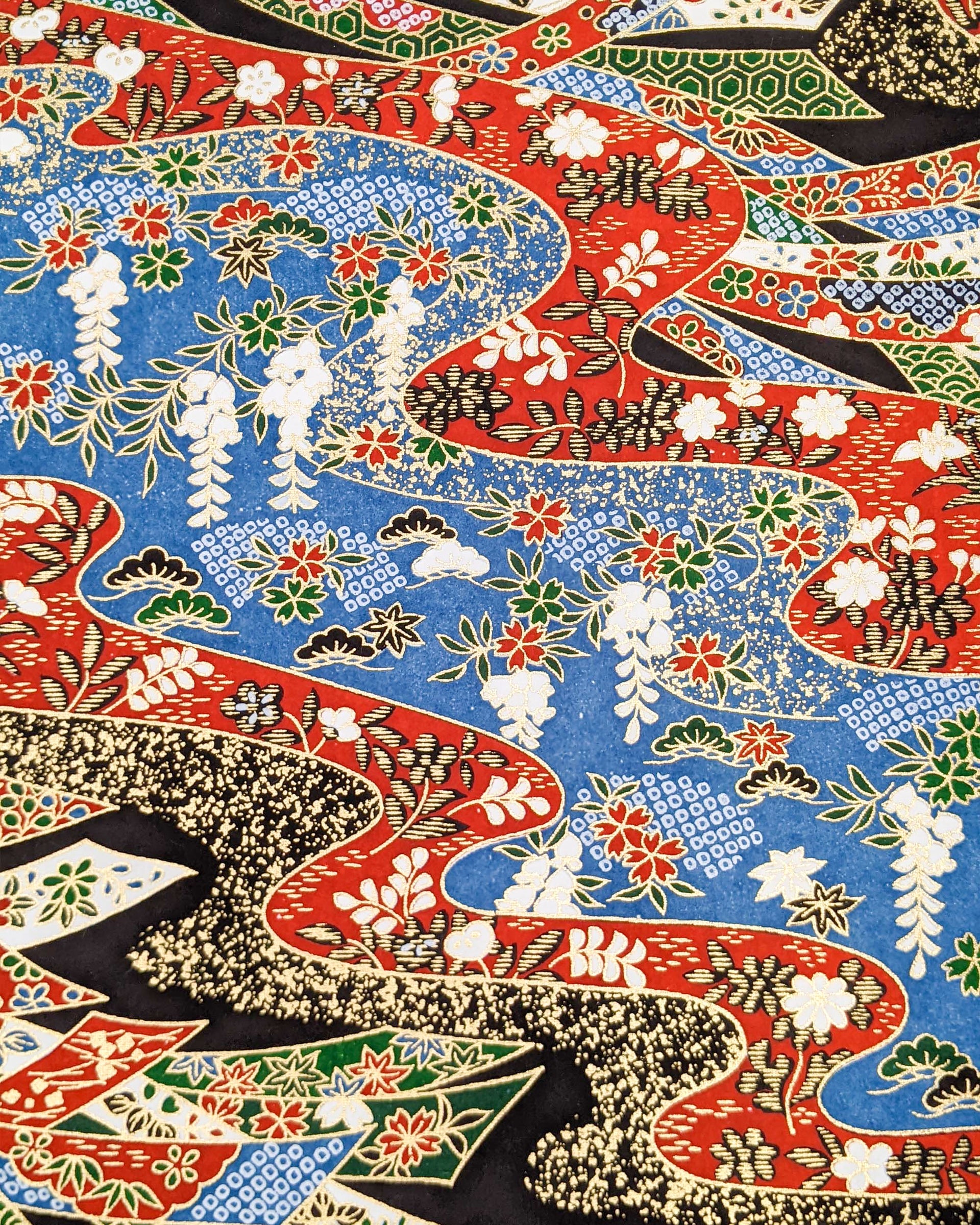 Japanese chiyogami paper featuring red, white, blue, and green ribbons decorated with traditional Japanese motifs on a black, blue, and red background with metallic gold details. The design includes scattered red and green cherry blossoms, green and black pines, red and black maples leaves, and white wisterias.