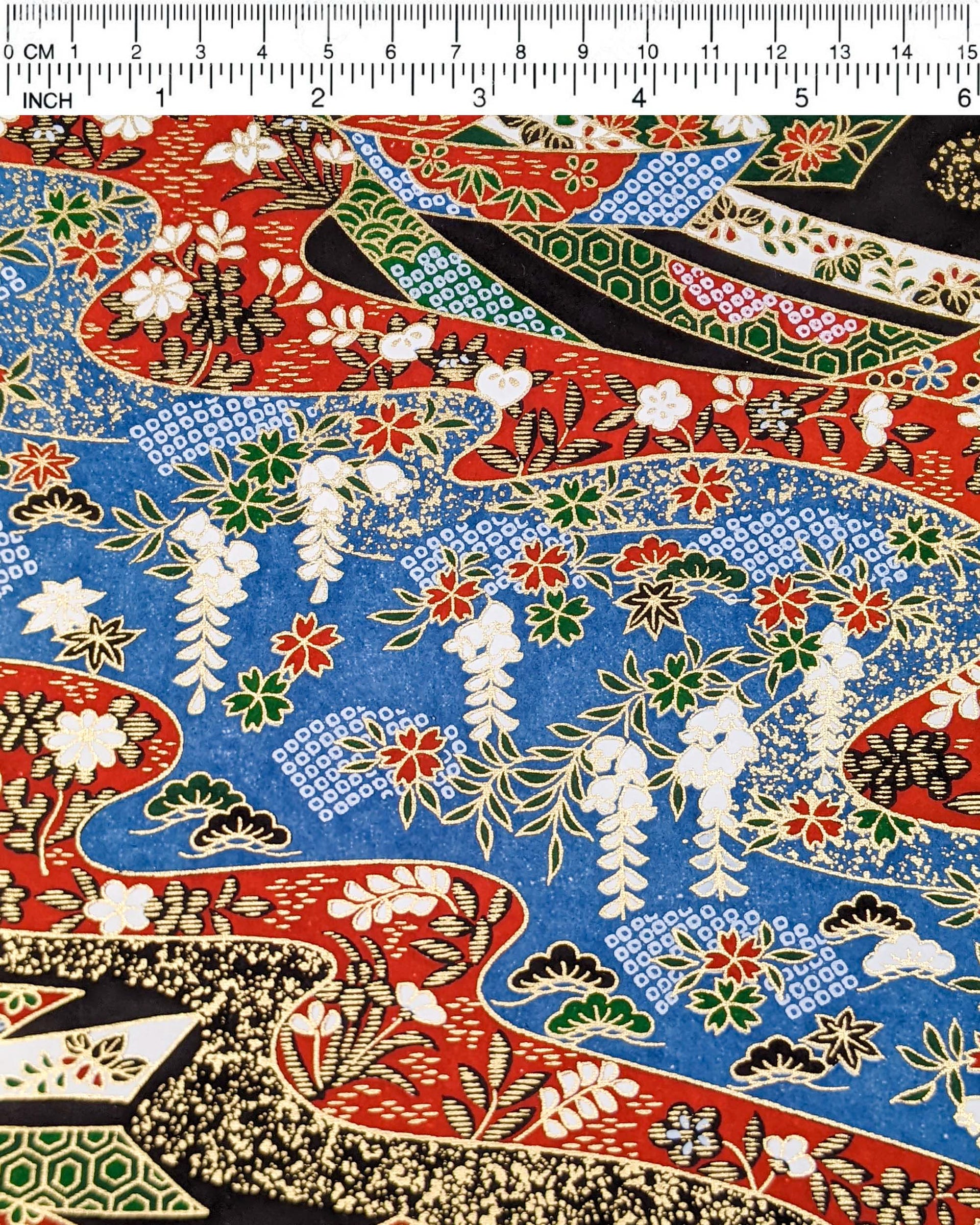 Japanese chiyogami paper featuring red, white, blue, and green ribbons decorated with traditional Japanese motifs on a black, blue, and red background with metallic gold details. The design includes scattered red and green cherry blossoms, green and black pines, red and black maples leaves, and white wisterias.
