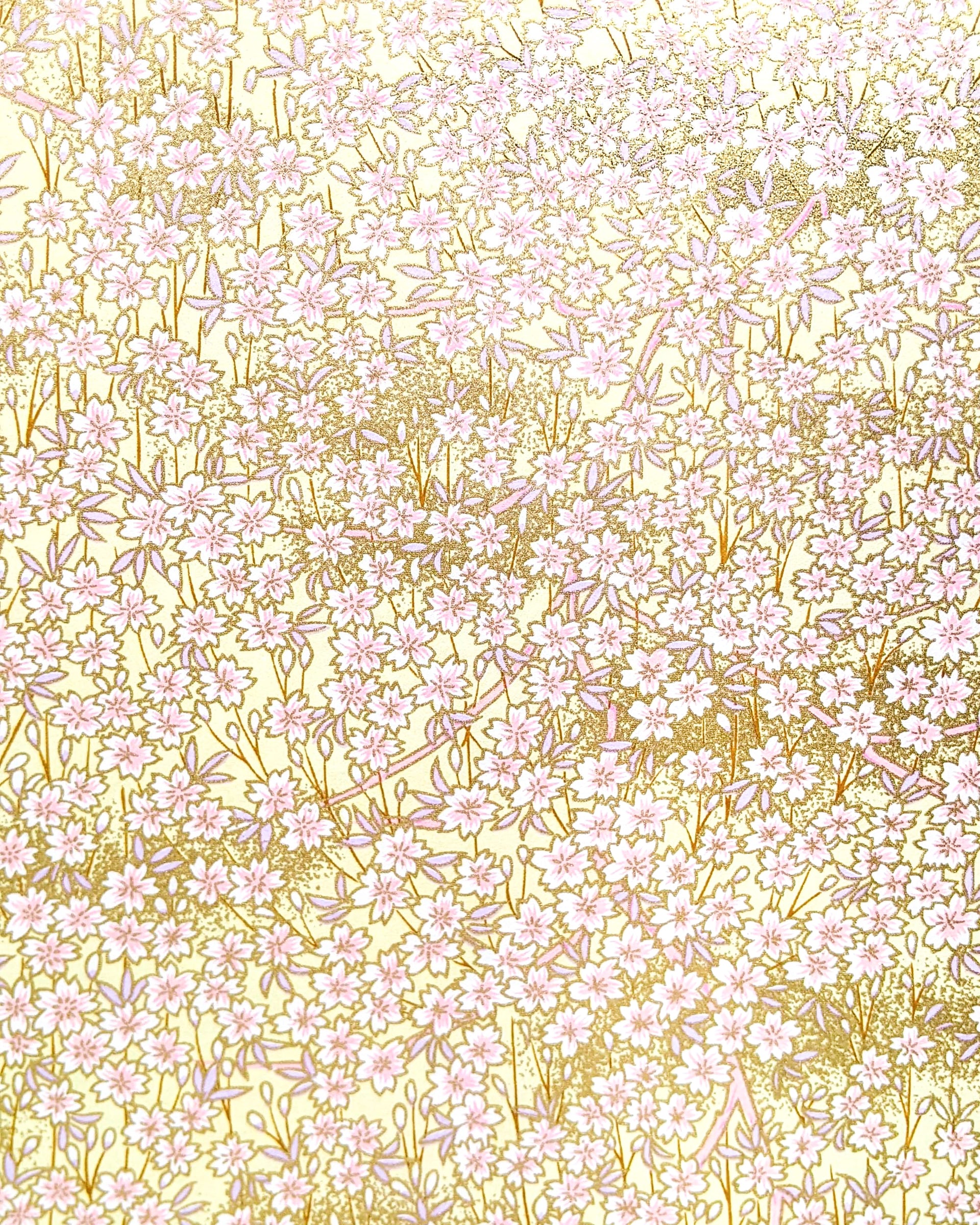 Japanese chiyogami paper featuring small white and light pink cherry blossoms on a yellow background with metallic gold details. 