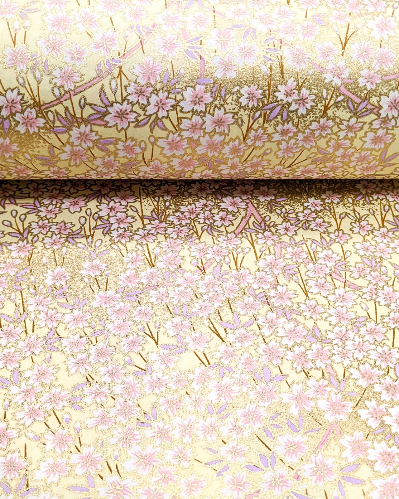 Japanese chiyogami paper featuring small white and light pink cherry blossoms on a yellow background with metallic gold details. 