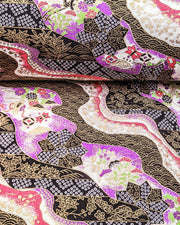 Japanese chiyogami paper featuring an assortment of purple, pink, and green flowers, flower cart motifs (hanaguruma), and traditional Japanese geometric designs with metallic gold details. The background is a mix of white, pink, purple, and black.