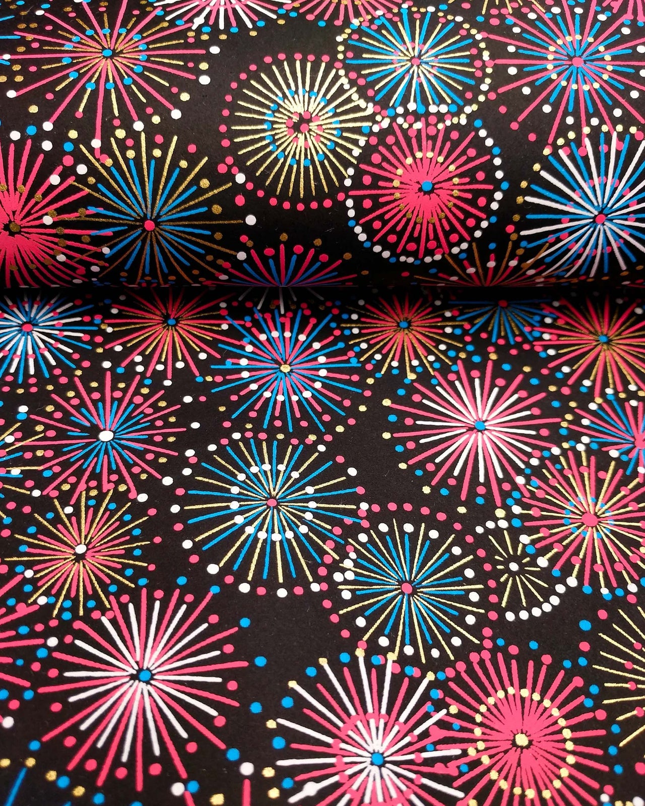Japanese chiyogami paper featuring colorful red, blue, pink, and white exploding fireworks on a black background with metallic gold accents.