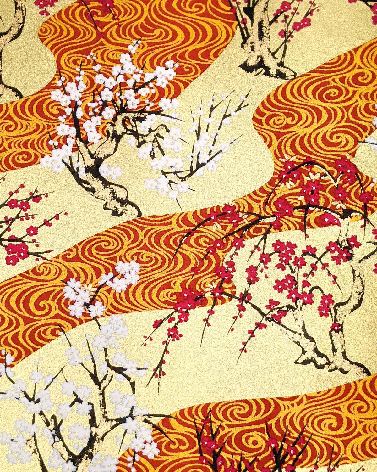 Japanese chiyogami paper featuring pink and white plum and cherry blossom trees set against a metallic gold and red water ripple pattern on a gold background.
