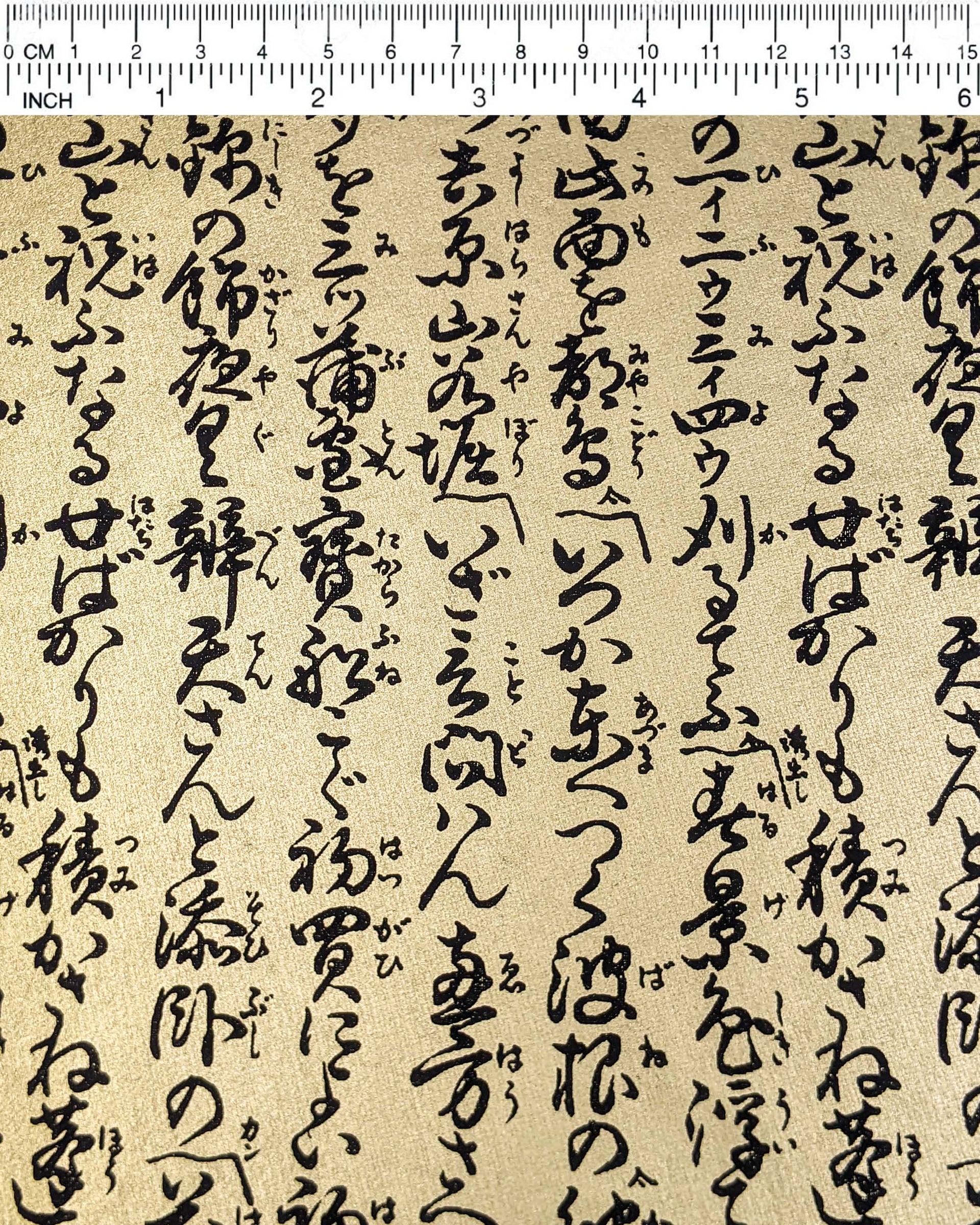 Japanese chiyogami paper featuring black Japanese calligraphy on a metallic gold background, shown next to a ruler for size reference.