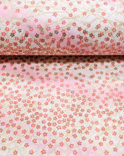 Japanese chiyogami paper featuring small red and metallic gold cherry blossoms on a gradient light pink background, shown rolled to highlight the design.