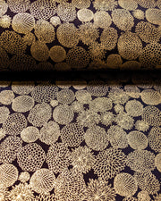 Japanese chiyogami paper featuring an assortment of small metallic gold chrysanthemums on a black background, shown rolled to highlight the design.