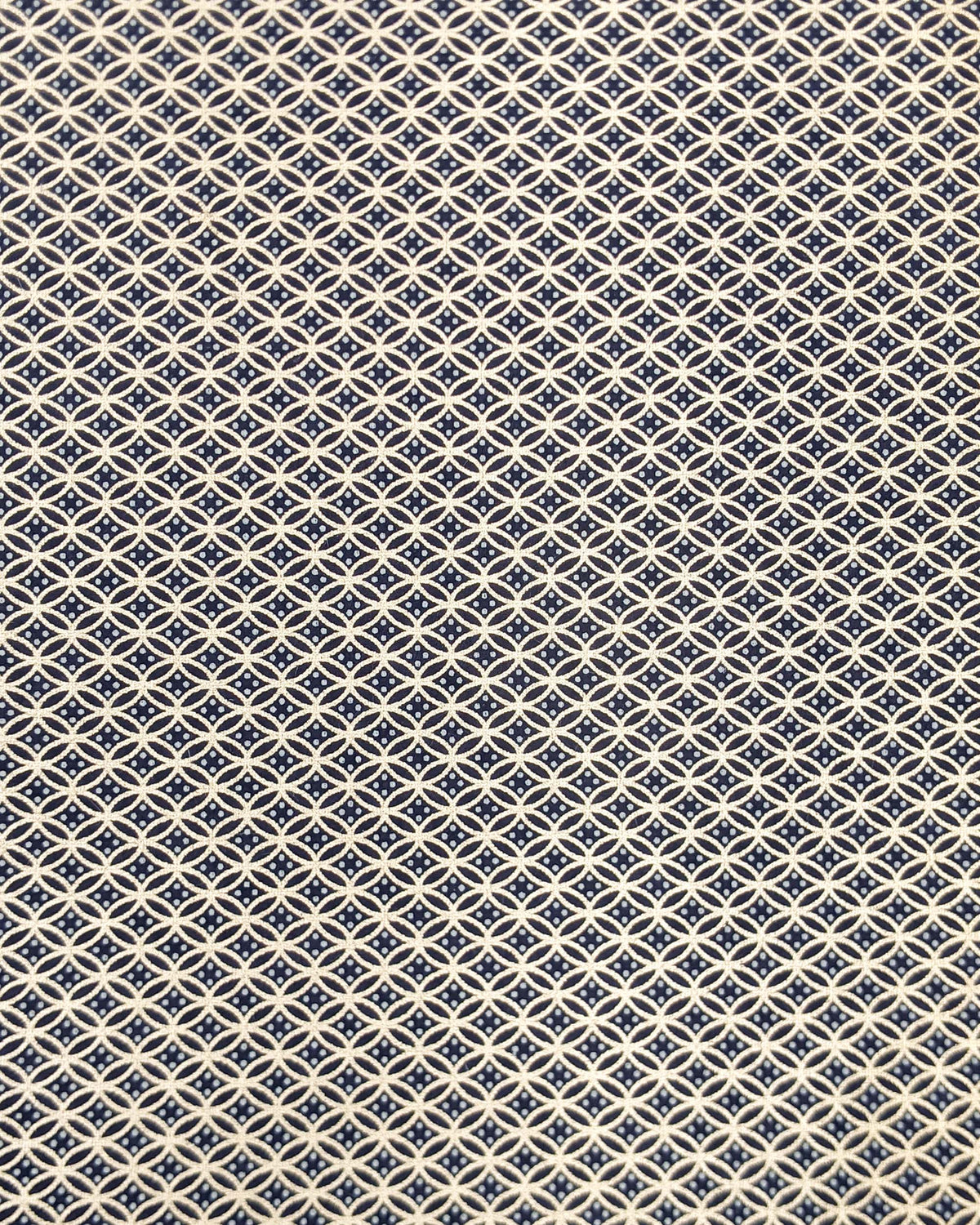 Japanese chiyogami paper featuring a traditional oval shippo pattern in metallic gold with four white dots in the center on a black background.