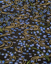 Japanese chiyogami paper featuring small blue maples leaves with green branches over flowing metallic gold streams on a black background.