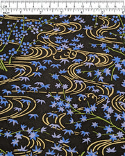 Japanese chiyogami paper featuring small blue maples leaves with green branches over flowing metallic gold streams on a black background, shown next to a ruler for size reference.