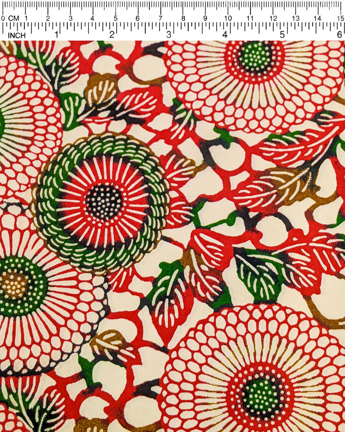 Japanese chiyogami paper featuring large red and green zinnia flowers on a cream background, shown next to a ruler for size reference.
