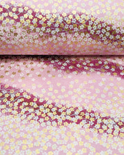 Japanese chiyogami paper featuring small white and metallic gold cherry blossoms on a gradient purple background, shown rolled to highlight the design.