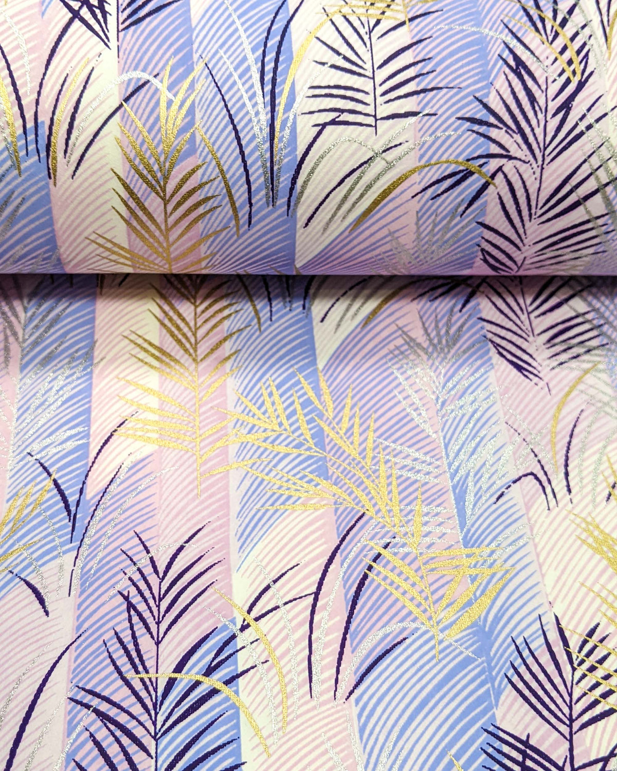 Japanese chiyogami paper featuring metallic gold, silver, and dark purple leaves on a vertically striped light purple background, shown rolled to highlight the design.