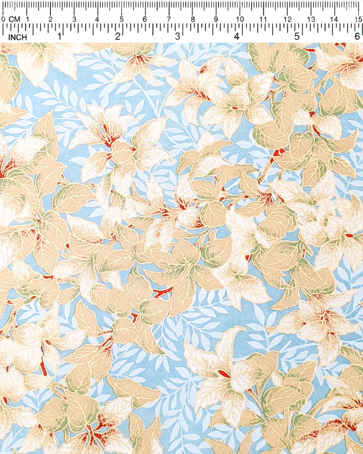 Japanese chiyogami paper featuring beige and white leaves with light blue leaves on a light blue background with metallic gold details, shown next to a ruler for size reference.